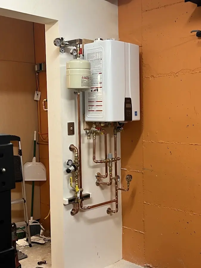 Plumbing technician inspecting water heater connections in Big Rapids